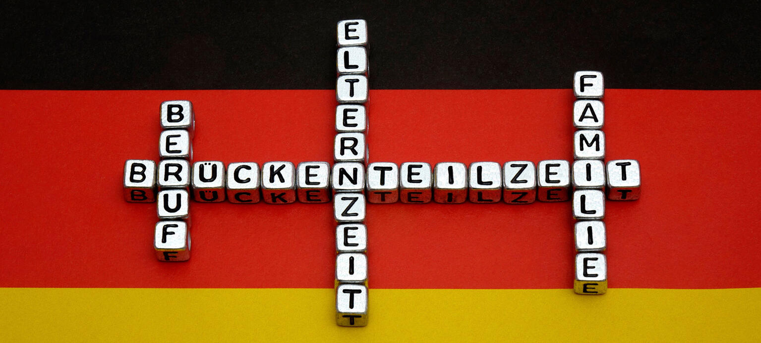 Auf einer Deutschlandfahne liegen Begriffe zur Brückenteilzeit.