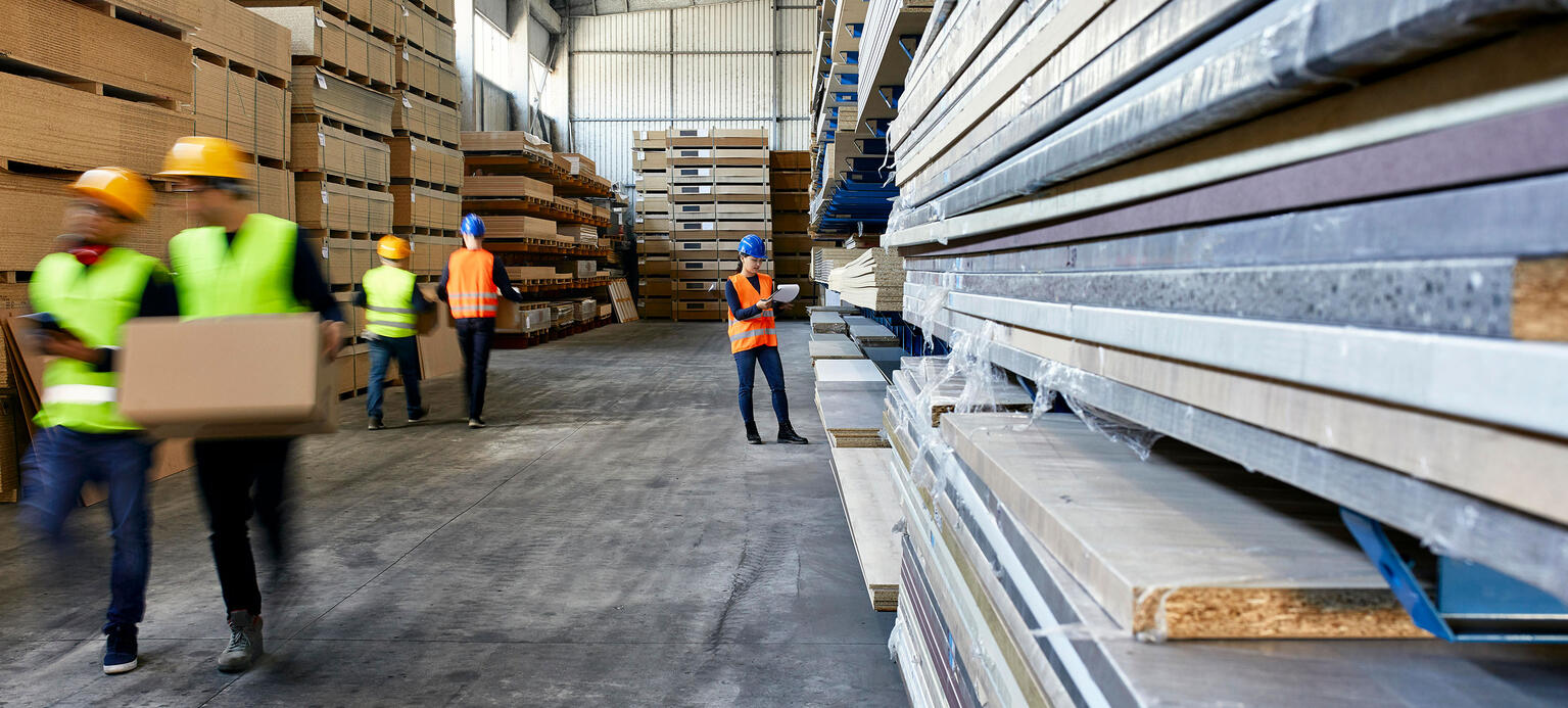 Arbeiter tragen Pappkartons in einer Lagerhalle.