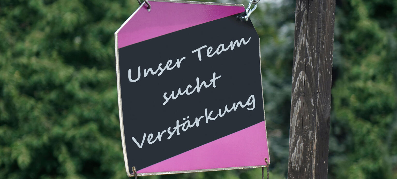 Auf einem Schild befindet sich der Schriftzug unser Team sucht Verstaerkung.